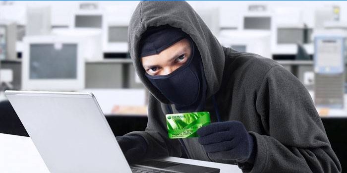Tip maskiran iza laptopa i s karticom u ruci