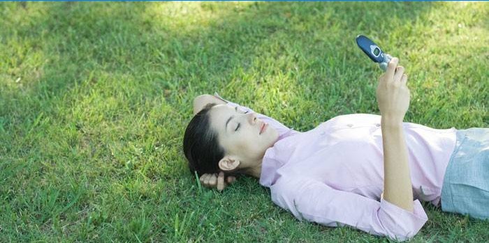Djevojka leži na travi s telefonom