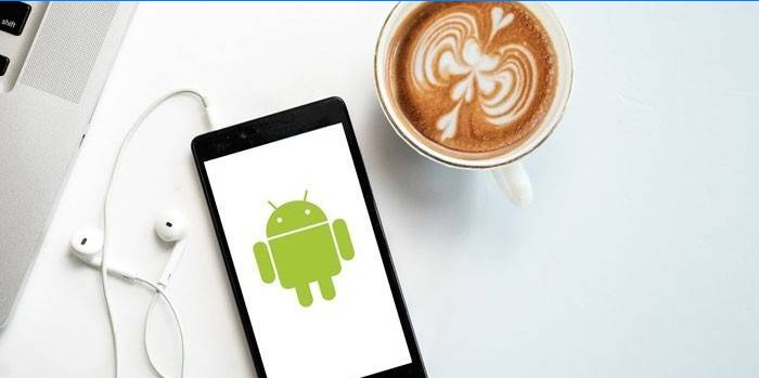 Smartphone sa slušalicama i šalicom kave.