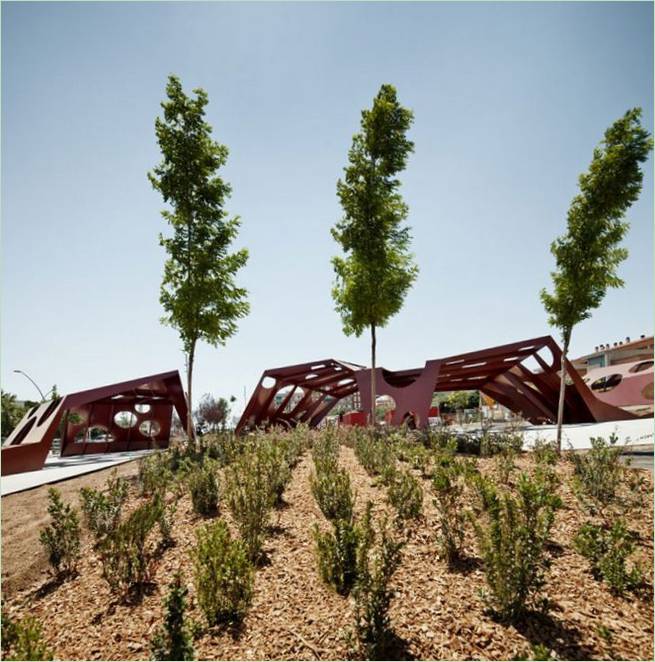 Mali grmovi i velika stabla u parku sa skulpturama